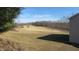 Large, sunny backyard with a gently sloping lawn and tree line in the distance at 1588 E Us Highway 136, Hillsboro, IN 47949