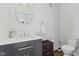 A quaint bathroom with a modern dark vanity, a round mirror, and a toilet at 234 N State Ave, Indianapolis, IN 46201