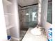 Bathroom featuring marble-style tile, glass shower doors, a white toilet, and a granite vanity top with a sink at 401 W Edwards Ave, Indianapolis, IN 46217