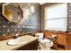 Traditional bathroom with floral wallpaper, wood paneling, octagonal mirror, and vanity with beige countertop at 426 Oakwood Dr, Indianapolis, IN 46260
