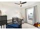 Bright Bedroom featuring a window, black crib, ceiling fan, and comfortable rocking chair at 4425 Maize Ln, Whitestown, IN 46075