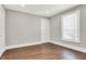 A simple bedroom is brightened by natural light from the window with blinds and has hardwood floors at 5053 E Michigan St, Indianapolis, IN 46201