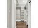 Walk-in closet featuring custom shelving, clothing rods, hardwood floors, and new paint and trim at 5053 E Michigan St, Indianapolis, IN 46201