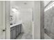 Bright bathroom with dual sinks, gray cabinets, quartz countertop, and tiled shower in the background at 5648 Juniper Ct, Whitestown, IN 46075