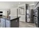 Modern kitchen with stainless steel appliances, gray cabinets, and a center island looking toward the living room at 5648 Juniper Ct, Whitestown, IN 46075