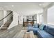 Open-concept living room with a staircase, blue sofa, and dining area leading to a kitchen with gray cabinets at 5648 Juniper Ct, Whitestown, IN 46075