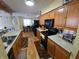 Spacious kitchen featuring warm wood cabinets, black appliances, and a view to the dining area at 5816 Coppock Ln, Indianapolis, IN 46221