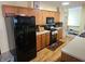 Well-equipped kitchen with wood cabinets, black appliances and light hardwood flooring at 5816 Coppock Ln, Indianapolis, IN 46221
