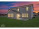 A spacious backyard featuring a patio, level lot, and home with gray siding and sunroom at dusk at 6723 Collisi Pl, Brownsburg, IN 46112