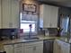 View of the sink, window, granite countertops and white cabinets in this well-lit kitchen at 686 N Sobota Way, Trafalgar, IN 46181
