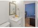 A well-lit bathroom with a single vanity, framed mirror, and a view into the next room at 6907 Buick Dr, Indianapolis, IN 46214