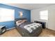 A contemporary bedroom featuring a dark gray bed, a blue accent wall, and natural light from two windows at 6907 Buick Dr, Indianapolis, IN 46214