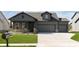 Craftsman style home with dark siding, brick accents, well-manicured lawn and three car garage at 7038 Barrett Dr, Brownsburg, IN 46112