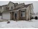 Two-story townhouse features a brick facade, attached garage, and snow-covered front yard at 8148 Shores Edge Way, Indianapolis, IN 46237