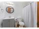 Bathroom features white cabinets and toilet, wood-look flooring and a round mirror at 11131 N State Road 9, Fountaintown, IN 46130