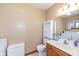 Bright bathroom with vanity, mirror, toilet, storage cabinet and laundry appliances visible in the background at 120 Saratoga Way, Anderson, IN 46013
