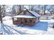 A cozy single-story home with a covered porch and detached garage sits amidst a snow-covered landscape and bare trees at 210 S West St, Paragon, IN 46166