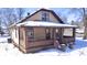 Cozy home featuring a welcoming covered porch with brick accents and tan siding, set against a snow-covered landscape at 210 S West St, Paragon, IN 46166