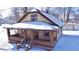 Charming single-story home with a brick-accented porch and detached garage, surrounded by a snow-covered yard at 210 S West St, Paragon, IN 46166
