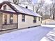 Charming home with a covered porch, vinyl siding and detached garage, all surrounded by snow at 210 S West St, Paragon, IN 46166