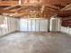 Empty garage space with unfinished ceiling and walls, a white overhead door and a concrete floor at 210 S West St, Paragon, IN 46166
