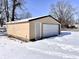Exterior view of a detached garage featuring an overhead door and a side entry door and snow in the yard at 210 S West St, Paragon, IN 46166