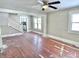 Open-concept living room with wood floors, a ceiling fan, and a view into the kitchen and staircase at 210 S West St, Paragon, IN 46166
