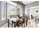 Bright dining area with a modern light fixture, large windows, and access to a cozy sunroom at 2487 Wayward Wind Dr, Indianapolis, IN 46239