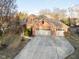 Aerial view of a traditional brick home with a spacious driveway and a three-car garage, nestled among mature trees at 2487 Wayward Wind Dr, Indianapolis, IN 46239