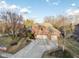 Aerial view of a well-maintained two-story brick home with a three-car garage, framed by mature trees and landscaping at 2487 Wayward Wind Dr, Indianapolis, IN 46239