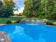 A private pool with a waterfall feature, surrounded by lush landscaping and a wrought iron fence for secure outdoor living at 2487 Wayward Wind Dr, Indianapolis, IN 46239