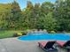 A backyard pool surrounded by lush landscaping, alongside a cozy lounge area featuring comfortable chairs for relaxation and enjoyment at 2487 Wayward Wind Dr, Indianapolis, IN 46239