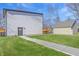 View of backyard with green grass, walkway, detached garage with door to yard, house siding, and blue sky at 3238 Guilford Ave, Indianapolis, IN 46205