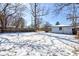 Large snowy backyard with a detached garage and trees under a clear blue sky at 4139 N Grand Ave, Indianapolis, IN 46226
