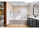 Bathroom featuring a tub with tiled surround and a gray vanity with modern fixtures at 4524 Moss Creek Ter, Indianapolis, IN 46237