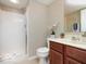 Bright bathroom featuring a shower with glass door, light beige walls, and modern cherry vanity at 9506 Oakley Dr, Indianapolis, IN 46260
