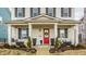 Inviting front porch with swing, red door with wreath, and professionally landscaped garden at 15432 Heatherbank Dr, Westfield, IN 46074