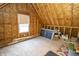 Unfinished attic featuring exposed beams, plywood walls, and a window, offering potential for expansion at 15921 Herriman Blvd, Noblesville, IN 46060