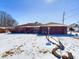 Single-story home featuring an attached garage, charming curb appeal and snow-covered lawn at 2021 E 9Th St, Anderson, IN 46012