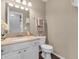 Well-lit half bath with granite counters and a decorative vanity mirror at 2311 Lammermoor Ln, Indianapolis, IN 46214