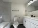 Contemporary bathroom featuring gray tiled walls, a modern vanity, toilet, and sleek black fixtures at 2411 N Kitley Ave, Indianapolis, IN 46219