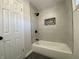 Modern bathroom featuring gray tiled walls, a bathtub with a stylish shower, and sleek black fixtures at 2411 N Kitley Ave, Indianapolis, IN 46219