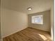 Bright bedroom features light colored walls, wood floors, a modern light fixture, and a window with natural light at 2411 N Kitley Ave, Indianapolis, IN 46219