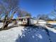 Charming single-story home with brick and light blue siding, complemented by a detached garage and snowy landscape at 2411 N Kitley Ave, Indianapolis, IN 46219