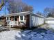 Charming single-story home featuring a brick facade, light blue siding, and a detached garage during winter at 2411 N Kitley Ave, Indianapolis, IN 46219