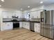 Renovated kitchen with sleek stainless steel appliances, white cabinetry, and modern hardwood flooring at 2411 N Kitley Ave, Indianapolis, IN 46219