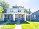 Charming two-story duplex featuring a landscaped front yard, inviting porch, and classic architectural details at 3419 Carrollton Ave, Indianapolis, IN 46205