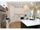 Bright kitchen features white cabinets, stainless steel appliances, marble backsplash, a black island, and hardwood floors at 3841 Falls Cir, Carmel, IN 46033