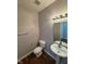 Clean half bathroom featuring a pedestal sink, toilet, and modern lighting fixture at 5142 Tuscany Ln, Indianapolis, IN 46254