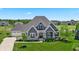 Charming two-story home with manicured lawn, gray siding, stone accents, and a three-car garage at 565 Old Ashbury Rd, Westfield, IN 46074